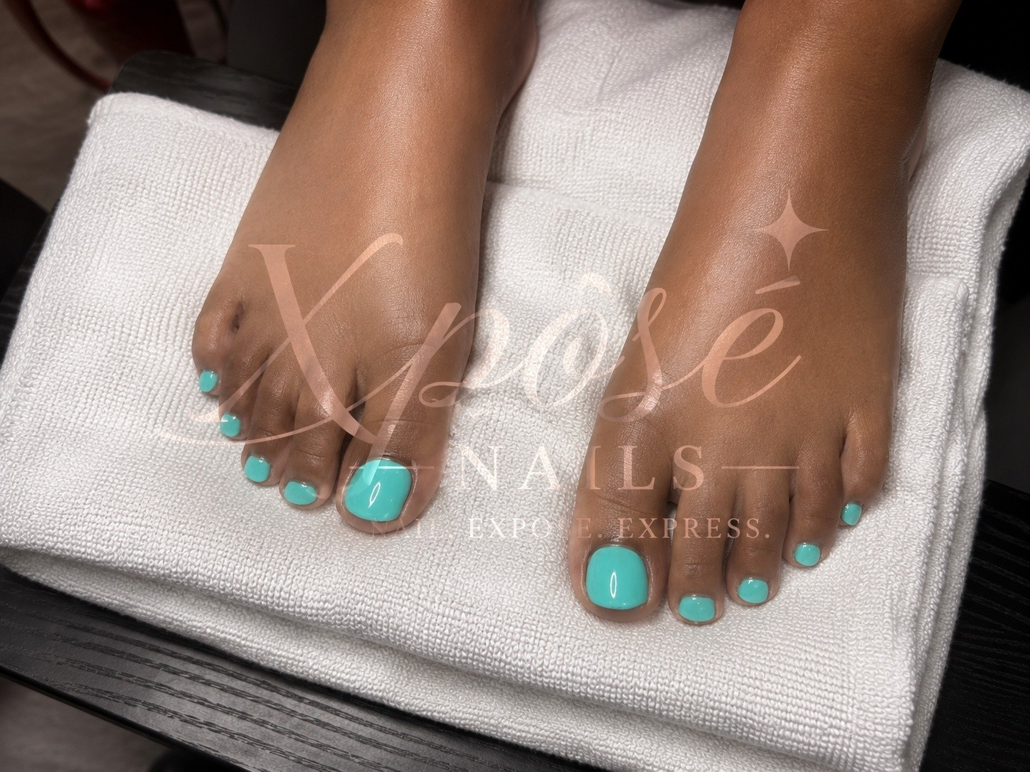 Teal gel pedicure on a white towel by Xposé Nails